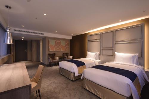 a hotel room with two beds and a desk at Green World ZhongXiao in Taipei