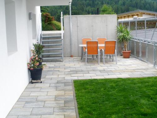 a patio with orange chairs and a table and grass at Ferienhaus Sporer in Iselsberg