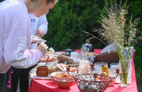 a woman eating food on a table with a red table cloth at Holiday home on farm (La Ferme du Tao) in Beaugies-sous-Bois