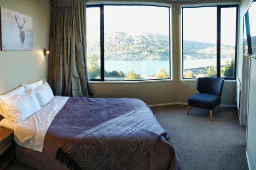 a hotel room with a bed and a chair and large windows at GoldRush Haven in Queenstown