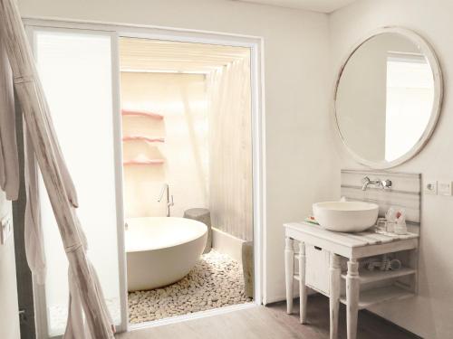 bagno con vasca, lavandino e specchio di HARRIS Hotel & Residences Sunset Road a Kuta