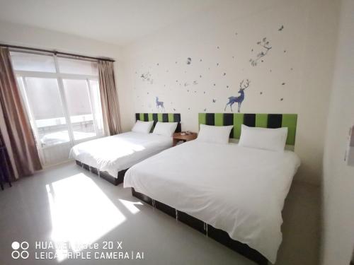 1 dormitorio con 2 camas y un ciervo en la pared en 玖號民宿, en Jincheng