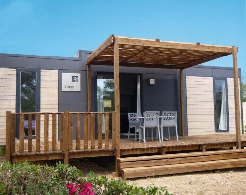 a tiny house with a deck and chairs on it at Camping Domaine du Lac Chambon in Murol