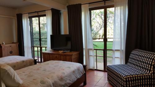 a bedroom with a bed and a television and a couch at Casa Khaoyai Bed&Breakfast in Mu Si