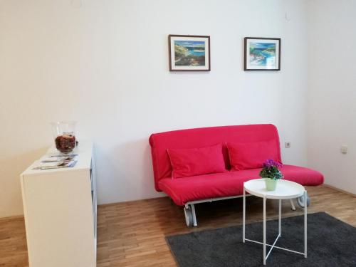 a red couch in a living room with a table at City center apartment in Umag