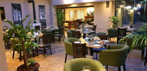 a restaurant with tables and chairs and plants at Granny Mouse Country House & Spa in Balgowan
