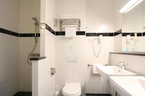 Bastion Hotel Vlaardingen في فلاردنغن: حمام ابيض مع مرحاض ومغسلة