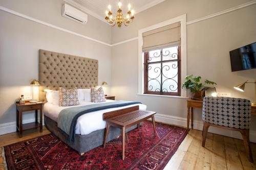 a bedroom with a bed and a table and a window at Bonne Esperance Boutique Guest House in Stellenbosch