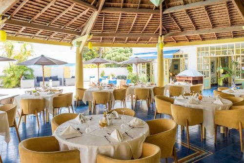 a restaurant with white tables and chairs and umbrellas at Le Nautile Beachfront in Saint-Gilles les Bains