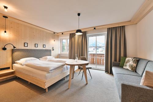 1 dormitorio con 2 camas, mesa y sofá en Hotel Bianca, en Lech am Arlberg