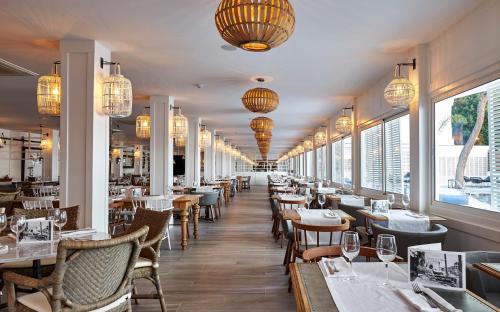 a restaurant with tables and chairs and chandeliers at Delamar 4*Sup-Adults only (18+) in Lloret de Mar