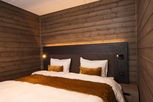 Svalbard Hotell | Lodge في لونغييربين: غرفة نوم بسرير كبير وبجدران خشبية