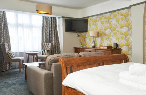 a hotel room with a bed couch and a tv at The Angel Inn Hotel in Pershore