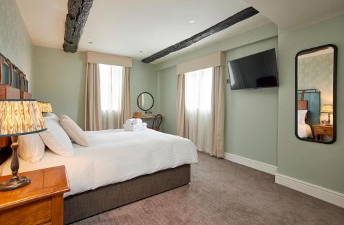um quarto com uma cama grande e um espelho em The Angel Inn Hotel em Pershore