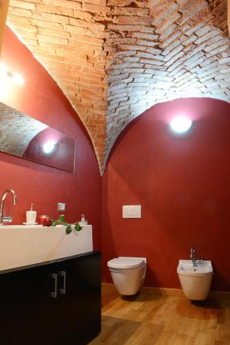 a bathroom with a sink and a toilet and a brick wall at Relais Palazzo Paleologi Sec.XIV in Lu