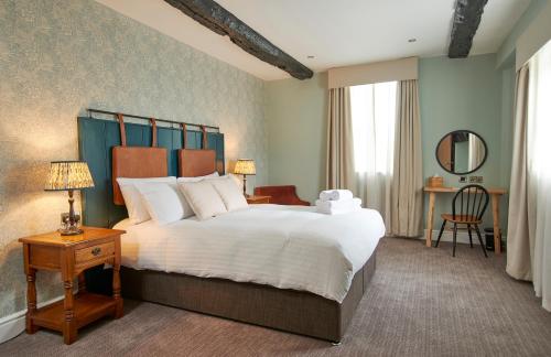a bedroom with a large white bed and a desk at The Angel Inn Hotel in Pershore