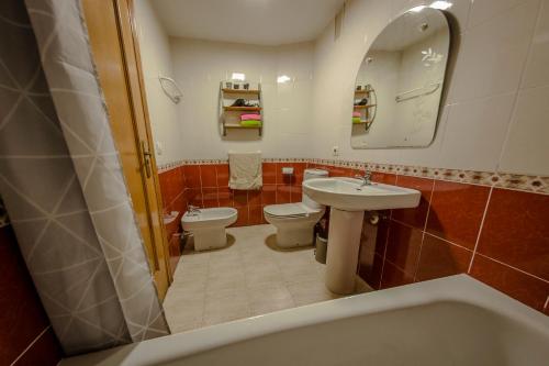 y baño con 2 aseos, lavamanos y bañera. en Apartamento Gandia Touriplaya, en Gandía