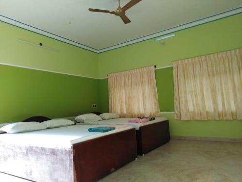 two beds in a room with green walls at VLS Holiday Home in Kanyakumari