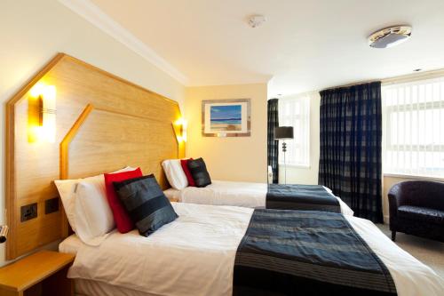 une chambre d'hôtel avec deux lits et une chaise dans l'établissement Queens Mansions: Empress Suite, à Blackpool