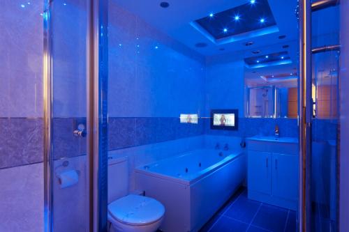 a blue bathroom with a tub and a toilet and a sink at Queens Mansions: Empress Suite in Blackpool