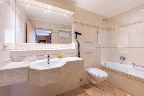 a bathroom with a sink and a toilet and a tub at Hotel Perrin - former Carlton in Luxembourg
