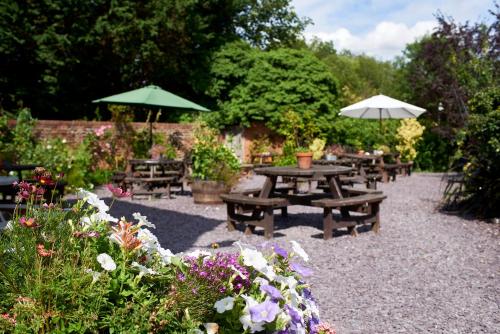 a group of picnic tables and umbrellas in a garden at The Angel Inn Hotel in Pershore
