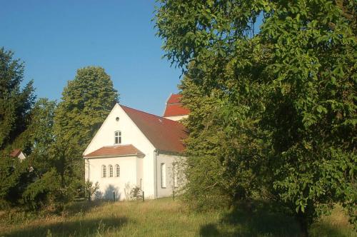 a white house with a red roof in a field at Appartements am Dorfkrug _ Ferienw in Freienhufen