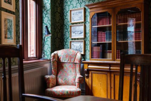 a room with a chair and a book shelf with books at City Centre Mansion Sleeping 1 to 23 in Cardiff