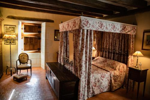 a bedroom with a canopy bed and a chair at Manoir Du Bois Noblet in Louerre