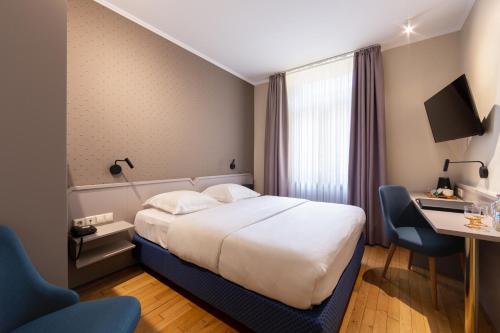 a hotel room with a bed and a desk at Hotel Perrin - former Carlton in Luxembourg