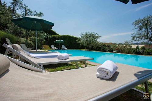 a pool with a table and chairs and an umbrella at Terre di Melazzano - Le Case di Chiara in Greve in Chianti