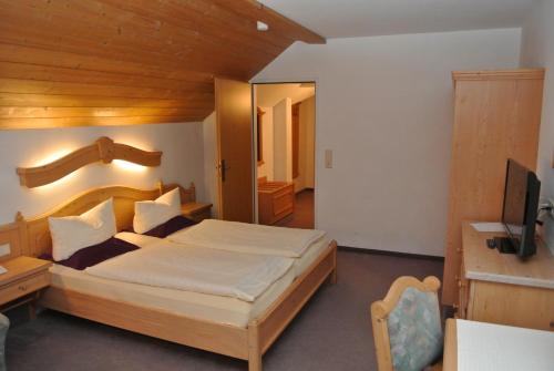a bedroom with a large bed and a television at Hotel Gruberhof Innsbruck Igls B&B in Innsbruck