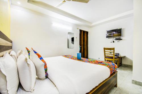 a bedroom with a white bed and a desk at FabHotel Grand Sheela in Patna
