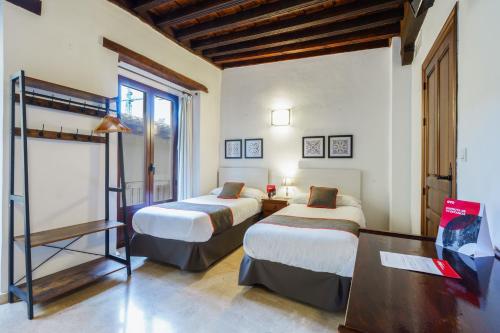 a hotel room with two beds and a desk at Casa Aljibe de Santa Ana in Granada