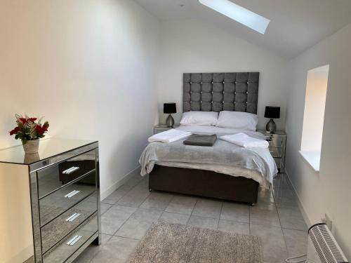 a bedroom with a large bed and a dresser and a bed sidx sidx sidx at COACHMAN COTTAGE OUTSIDE HOT TUB in Beith