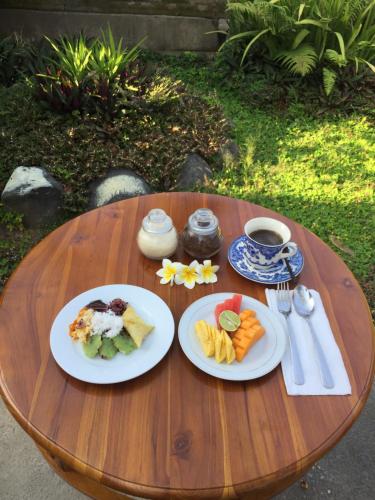 a wooden table with two plates of food on it at MALINI Homestay in Ubud