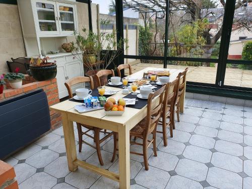 - une table en bois avec des chaises et des fruits sur la terrasse dans l'établissement Libération-Maison d'hotes, au Mans