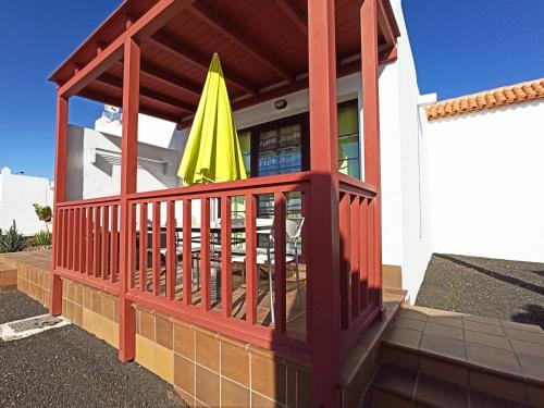 a patio with a table and a yellow umbrella at Sun Beach 89 in Caleta De Fuste