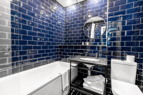 a blue tiled bathroom with a tub and a sink at The Park in Peebles