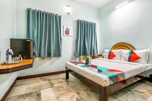 1 dormitorio con 1 cama y TV en FabExpress Santhi Inn, Promenade Beach en Pondicherry