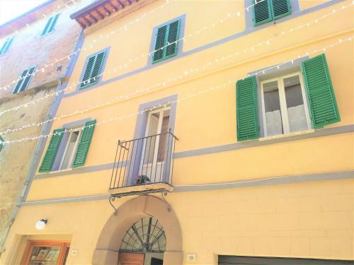 un edificio giallo con finestre con persiane verdi e balcone di La Casina in Paese a Montepulciano