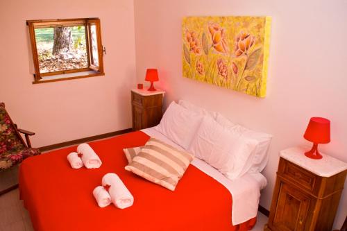 a bedroom with a red bed with slippers on it at Umbria Weekend in Cascia