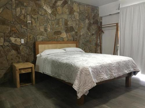 1 dormitorio con cama y pared de piedra en Suites Nativo - Beautiful Vineyard & Valley View, en Valle de Guadalupe