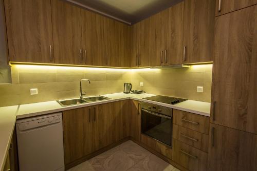 a kitchen with wooden cabinets and a sink and a stove at Regalo Apartments in Lygia