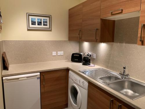 a kitchen with a sink and a washing machine at Hayfield Apartment in Lossiemouth