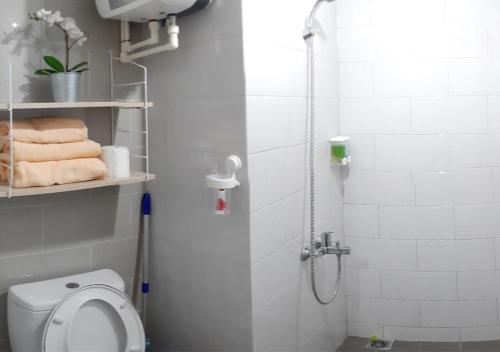 a bathroom with a toilet and a shower with towels at Apartemen Taman Melati Sinduadi 61 in Yogyakarta
