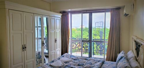 ein Schlafzimmer mit einem Bett und einem großen Fenster in der Unterkunft Spacious Apartment near the Beach in Masaki in Daressalam