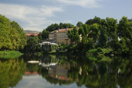 a view of a river with trees and buildings at Hotel Casa da Calçada Relais & Chateaux in Amarante