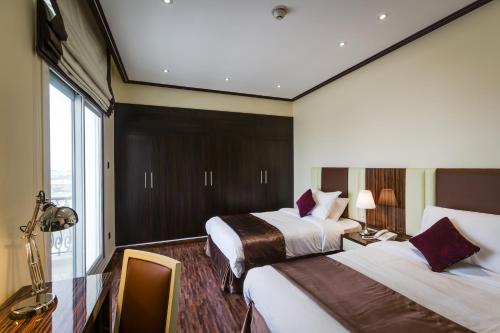 ein Hotelzimmer mit 2 Betten und einem Fenster in der Unterkunft The View Al Barsha Hotel Apartments in Dubai