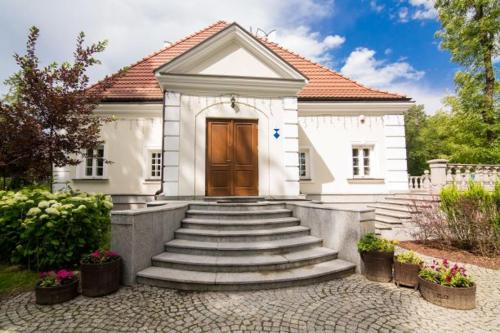 ein weißes Haus mit einer Treppe, die zu einer Tür führt in der Unterkunft Dwór Many, blisko do Suntago & DeepSpot in Many